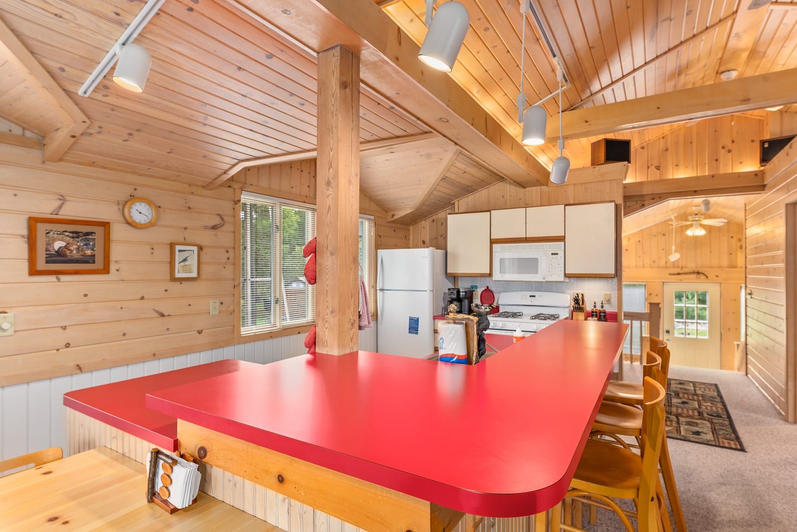 Living room with vaulted pine ceiling and large windows