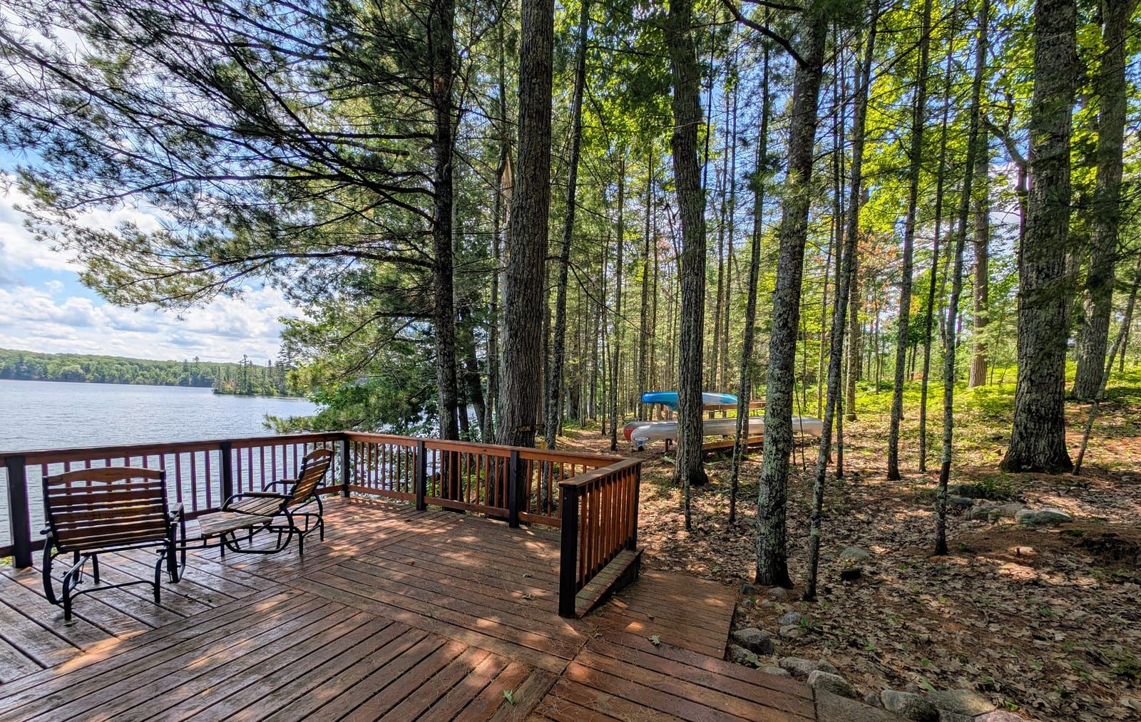 Lakeside deck with seating among tall pines