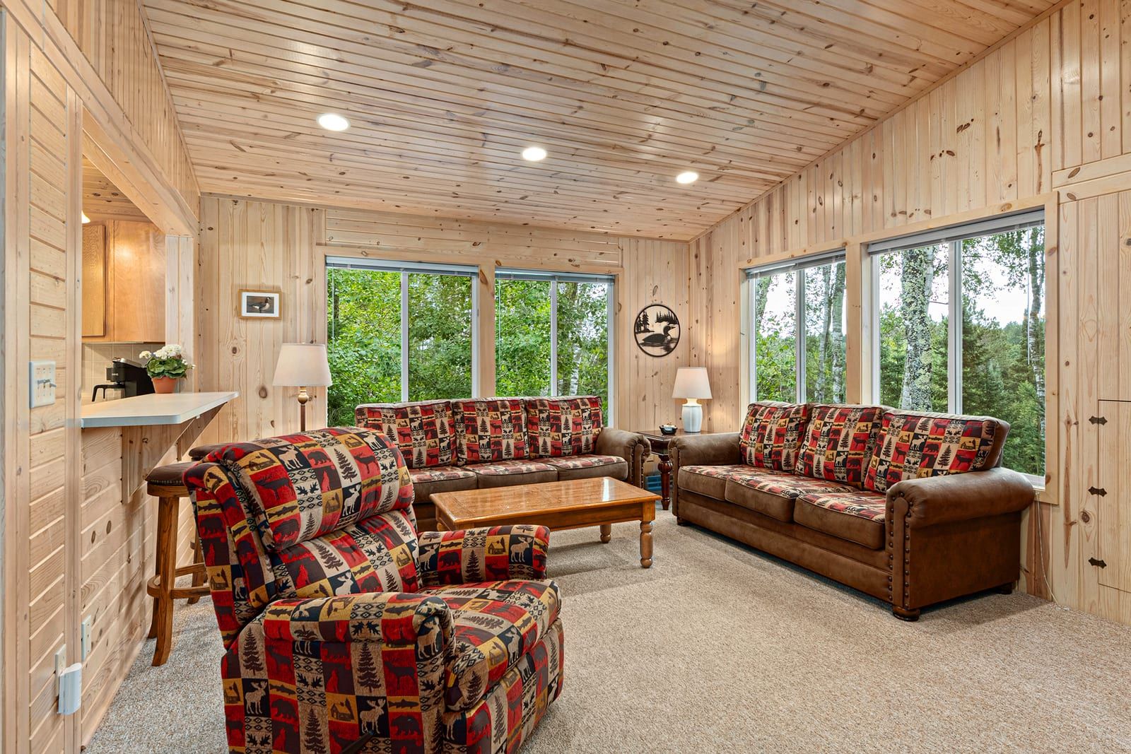 Living room seating area with pine walls and large windows